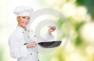 Smiling female chef with pan and spoon