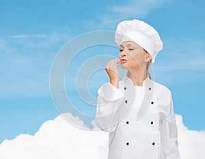 Smiling female chef showing delicious sign