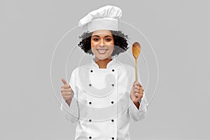 smiling female chef with spoon showing thumbs up