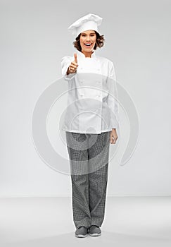 Smiling female chef in toque showing thumbs up