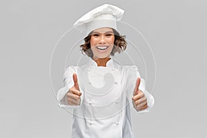 Smiling female chef in toque showing thumbs up