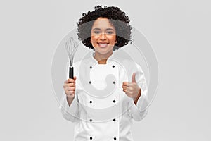 smiling female chef with whisk showing thumbs up