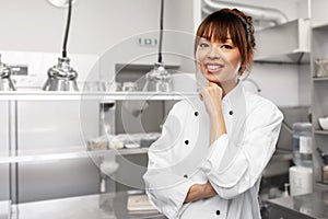 smiling female chef in white jacket at kitchen