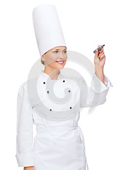 Smiling female chef writing something on air