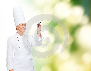 Smiling female chef writing something on air