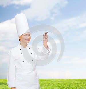 Smiling female chef writing something on air