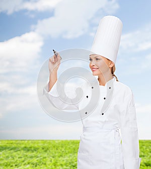 Smiling female chef writing something on air