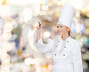 Smiling female chef writing something on air