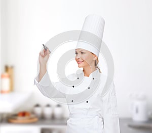 Smiling female chef writing something on air