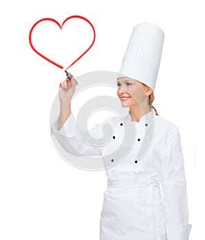 Smiling female chef writing something on air