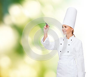 Smiling female chef writing something on air