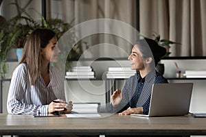 Smiling female colleagues brainstorm cooperate at office meeting