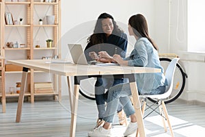 Smiling female colleagues brainstorm cooperating on laptop