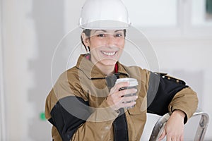 Smiling female construction worker having coffee break