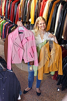 Smiling female customer satisfied with purchases in leather clothing boutique