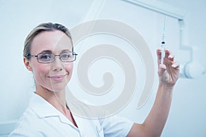 Smiling female dentist holding injection