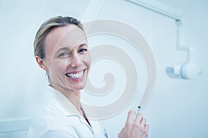 Smiling female dentist holding injection