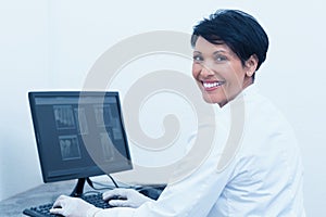Smiling female dentist with x-ray on computer