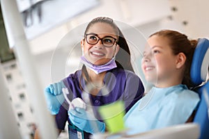 Dentist with girl in dental chair looking at her dental x-ray footage photo