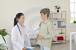 Smiling female doctor comforting boy patient in consultation in medical clinic