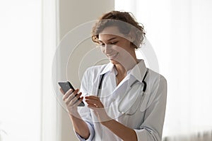 Smiling female doctor consult client on cellphone gadget