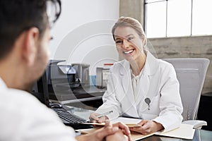 Smiling female doctor in consultation with male patient