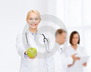 Smiling female doctor with green apple