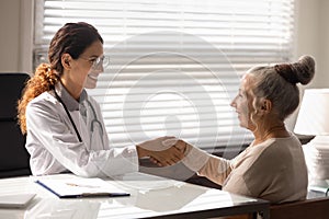 Smiling female doctor handshake mature woman patient