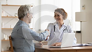 Smiling female doctor handshake senior male patient