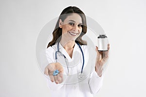 Smiling female doctor holding bottle of pills