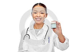 smiling female doctor holding jar of medicine