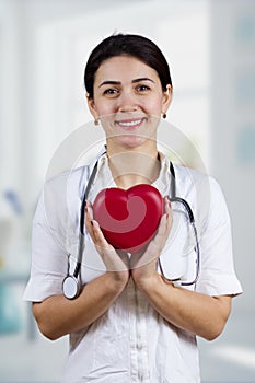 Smiling Female doctor holding red heart and stethascope