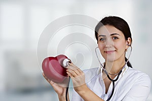 Smiling Female doctor holding red heart and a stethoscope