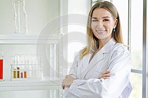 Smiling female doctor in lab coat with arms crossed against.