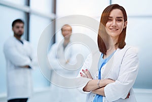 Smiling female doctor in lab coat with arms crossed against