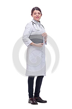 Smiling female doctor with lab coat in her office holding a clipboard with medical records