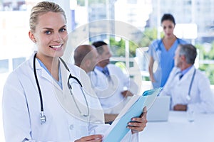 Smiling female doctor looking at camera while her colleages works