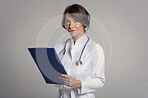 Smiling female doctor looking at camera and smiling while standing against at isolated background