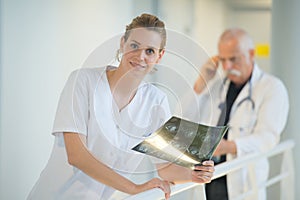 Smiling female doctor looking at x-ray in hospital corridor