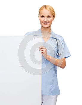 Smiling female doctor or nurse with blank board