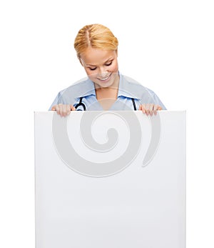 Smiling female doctor or nurse with blank board