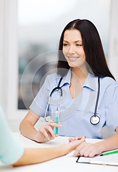 Smiling female doctor or nurse with syringe