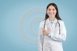 Smiling female doctor pointing to her side at free space