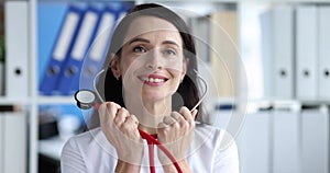 Smiling female doctor putting on stethoscope