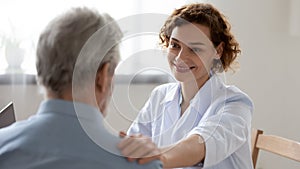 Smiling female doctor reassuring supporting senior patient in hospital