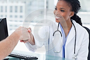 Smiling female doctor shaking a hand