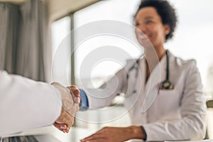 Smiling female doctor shaking hands with patient at hospital