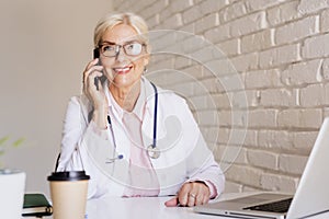 Smiling female doctor sitting at desk and working in the doctor`s office