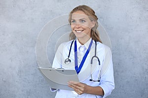 Smiling female doctor with stethoscope holding health card isolated over grey background