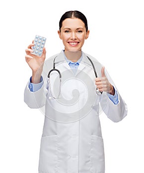 Smiling female doctor with stethoscope and pills